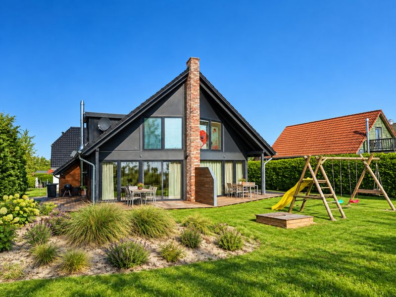 Garden side of the house with both wooden terraces, playground and sandpit